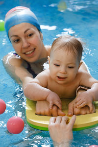 Swimming pool baby boy trained to swim in water healthy and sport family with infant, active parent