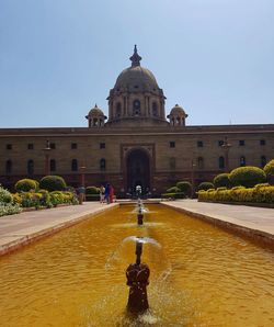 Fountain in front of historic building against sky