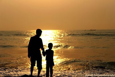 Silhouette of people on beach at sunset