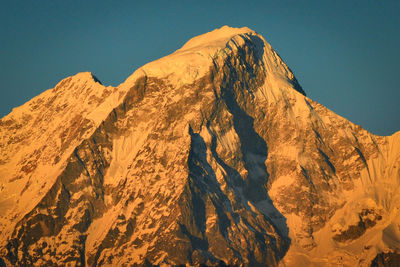 Low angle view of snowcapped mountains against clear sky