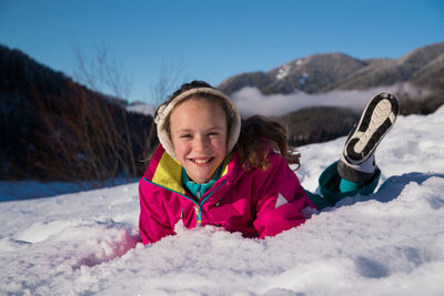 Portrait of smiling girl lying in snow