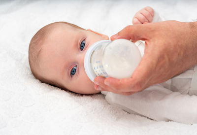 Midsection of woman holding bottle on bed at home