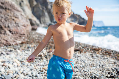 Low section of shirtless man standing at beach