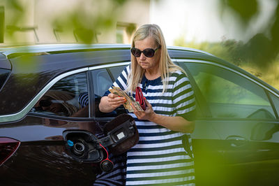 Worried woman with euro cash at the car, put money to car tank, the concept of rising fuel prices