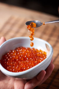 Close-up of hand holding caviar in bowl