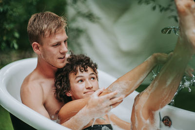 Portrait of shirtless man with baby in water