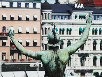 Rear view of statue against buildings on sunny day