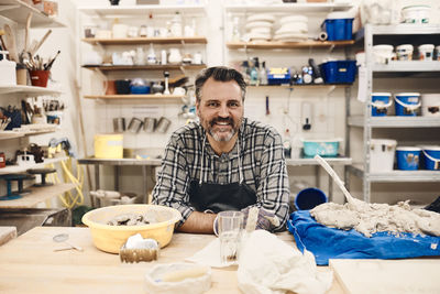 Portrait of smiling mature man sitting at table in art class