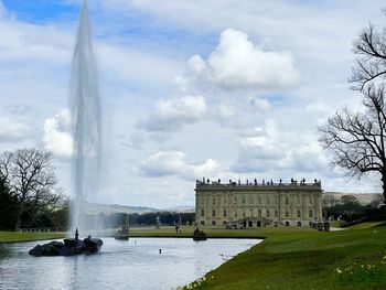 View of fountain in city against cloudy sky