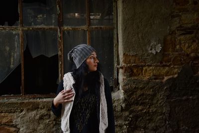 Woman standing against abandoned building