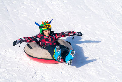 Full length of boy over inflatable raft on snow