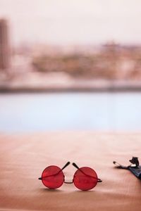 Close-up of sunglasses on table at beach against sky