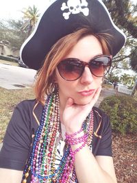 Portrait of young woman wearing sunglasses standing against trees