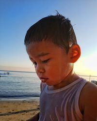 Close-up of boy on beach against sky