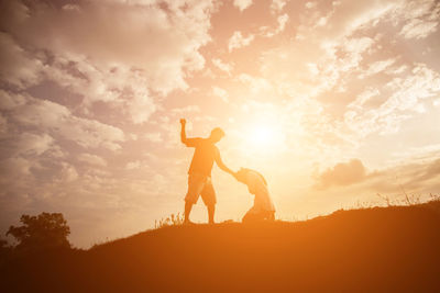 Silhouette man standing on field against sky during sunset