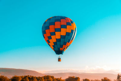 Low angle view of hot air balloon flying in mid-air against clear blue sky