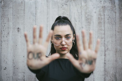 Portrait of young woman standing by text on wall