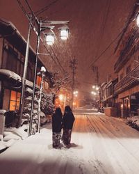 Rear view of woman walking on snow covered street at night