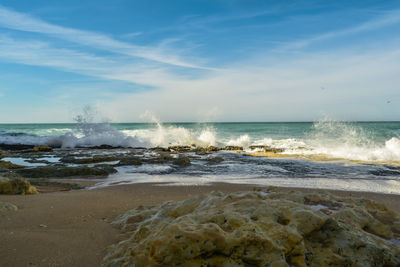 Waves splashing on shore against sky