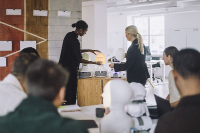 Mature female teacher explaining student over social robot in innovation lab