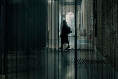 Rear view of silhouette woman walking in corridor of building