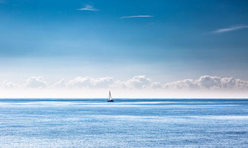 Sailboat in sea against blue sky