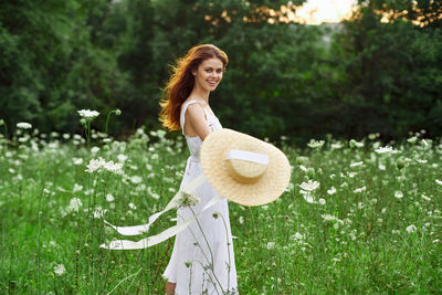 Young woman wearing hat standing against trees