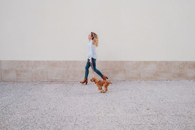 Full length of woman with dog against wall