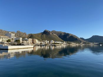 Scenic view of lake by buildings against clear blue sky