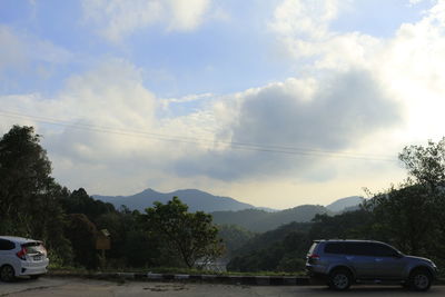 Cars on road against cloudy sky