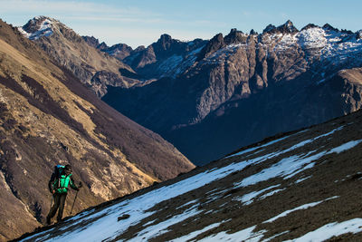 Hiker walking on snowcapped mountain during winter