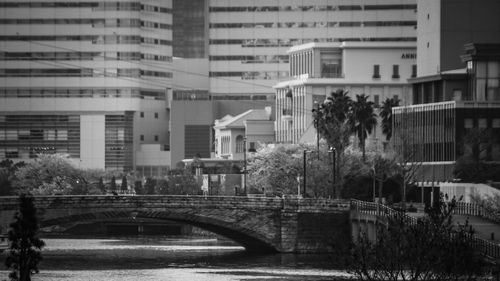 Arch bridge over river amidst buildings in city