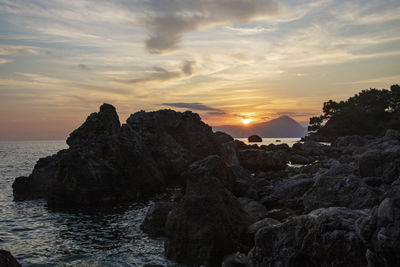 Rocks on sea against sky during sunset