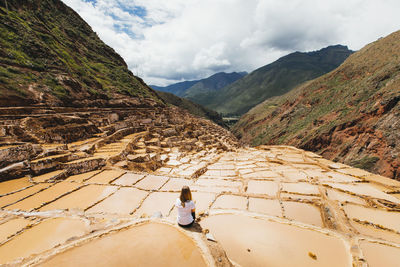 Young woman is sitting near the famous salt mines in peru