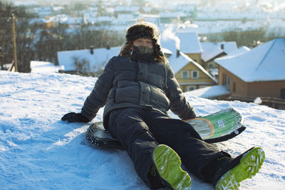 Boy sitting on snow covered landscape