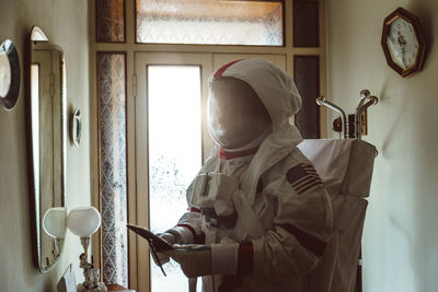Man using phone while wearing spacesuit at home