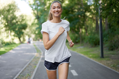 Portrait of a smiling young woman standing on road