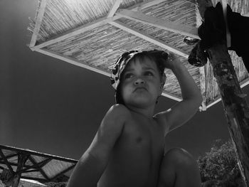 Low angle view of shirtless boy against sky