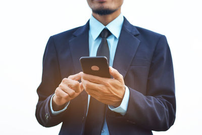 Midsection of man using smart phone against white background