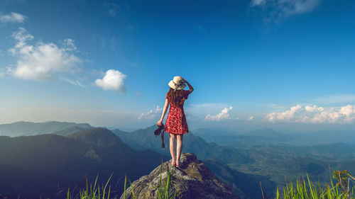 Rear view of woman standing on mountain against sky