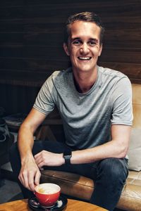 Portrait of a smiling young man sitting on table