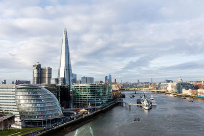 River amidst buildings in city against cloudy sky