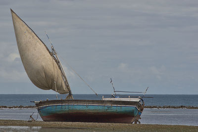 Boat moored on beach against sky