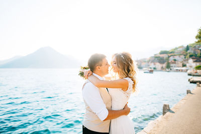 Couple standing near sea against sky