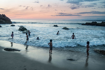 People on beach against sky during sunset