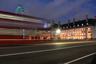 Light trails on road in city against sky at night