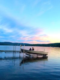 Boat moored in lake against sky during sunset