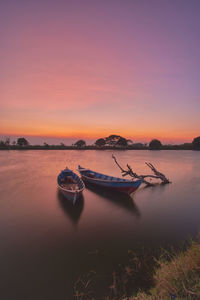 Two empty wooden boats for fishing on a calm water lake at sunset
