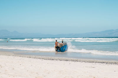 People on beach against clear sky