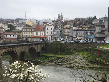 Bridge over river by buildings in town against sky